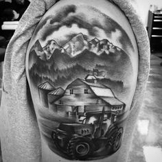 a black and white photo of a man's arm with a farm scene on it