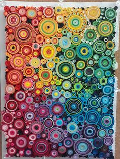 an art project made with colorful circles and dots on paper, hanging on a wall