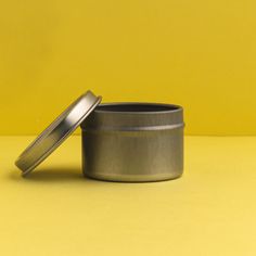 an empty tin can sitting on a yellow surface