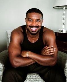 a man sitting on top of a chair with his arms crossed and smiling at the camera