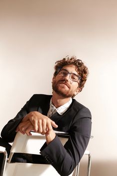 a man sitting in a chair with his hand on the seat and looking off to the side