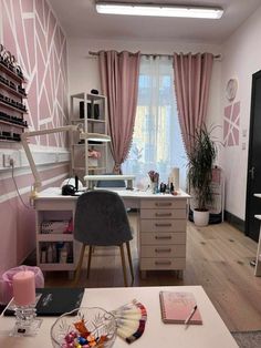 a room with a desk, chair, and window in the center is decorated with pink wallpaper