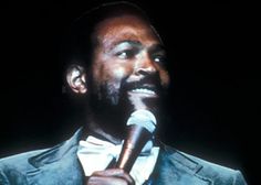 a man holding a microphone in his right hand while wearing a suit and bow tie