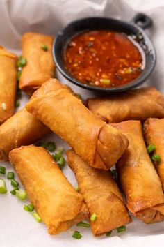 some food is laying out on a white plate with green onions and sauce in the background