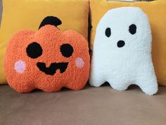 two halloween pillows sitting next to each other on a couch