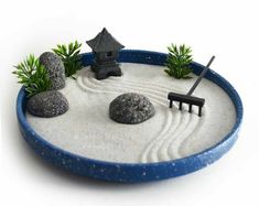 a miniature sand garden with rocks, plants and a house in the middle on a white background