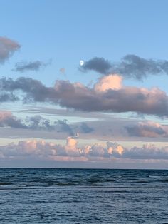 the sky is filled with white clouds and blue water as it sits in the ocean