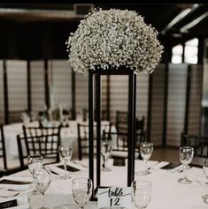 there is a tall vase with baby's breath flowers on it at the head table