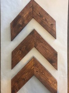 three wooden chevrons are mounted on the wall, one is white and the other is brown