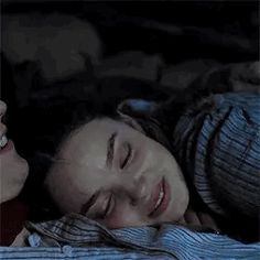 two women laying in bed next to each other and one is smiling at the camera