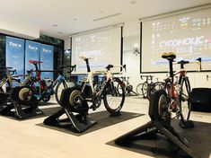 there are many bikes that are on display in this room with the projection screen behind them