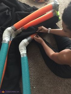 a woman laying on the floor working on some plastic pipes that are connected to each other