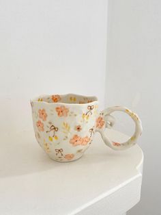 a cup sitting on top of a white table next to a wall with a keychain