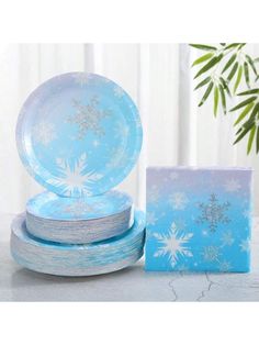 blue and white paper plates with snowflakes on them next to a potted plant