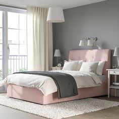 a bedroom with a pink bed and white curtains