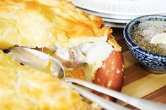 a close up of food on a wooden table with utensils and plates in the background