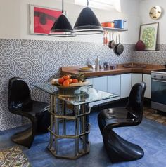 a kitchen with blue tile flooring and black chairs in front of a glass table