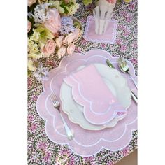 the table is set with pink and white plates, silverware, and napkins