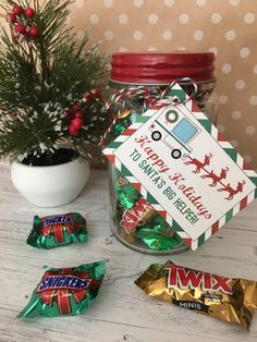 a jar filled with candy next to some christmas candies and a small potted tree