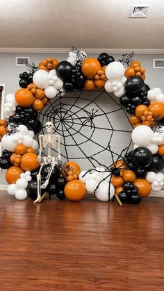 a halloween wreath made out of black, white and orange balloons with a skeleton in the center