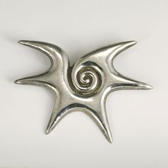 a silver brooch with spiral design on the front and back side, against a white background