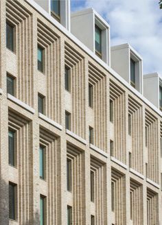 the building has many windows and is made out of bricks with vertical lines on each side