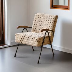 a chair sitting in front of a window next to a wall with a mirror on it