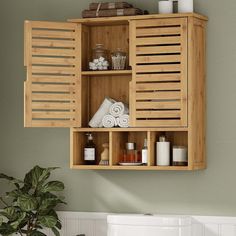 a wooden cabinet with towels, soaps and other items on it next to a potted plant