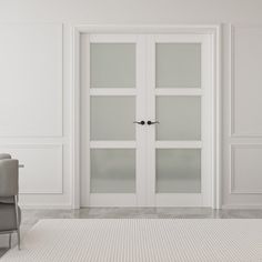 an empty white room with two chairs and a large glass door that leads to another room