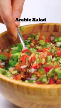 a person is cutting into a salad in a wooden bowl with the words arabic salad above it