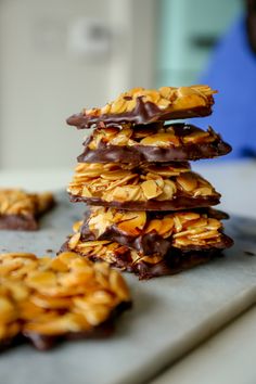 a stack of cookies sitting on top of a counter covered in chocolate and almonds