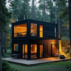 a house made out of shipping containers is lit up at night in the middle of the woods