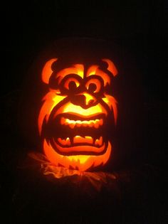 a pumpkin carved to look like a bear with its mouth open and teeth out, lit up in the dark