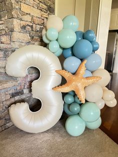 the number three made out of balloons and starfish is displayed in front of a brick wall