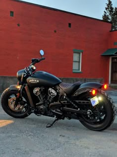 a black motorcycle parked in front of a red brick building with its lights turned on