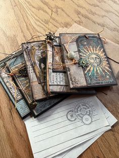 an assortment of cards and envelopes sitting on a wooden table with string attached to them