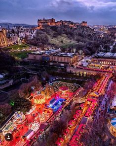 an aerial view of a fairground with lights and rides in the foreground at dusk