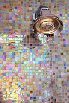 a faucet running from a shower head with colorful tiles on the wall behind it