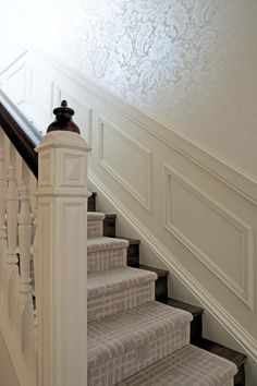 the stairs are lined with white carpet and decorative wallpaper