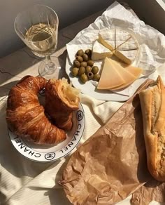 bread, cheese and olives are sitting on a table next to some wine glasses