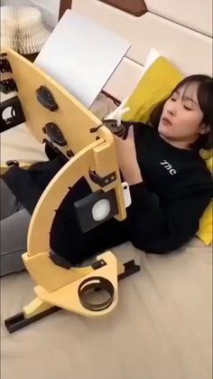 a woman laying on top of a bed next to a yellow object in the shape of a microscope