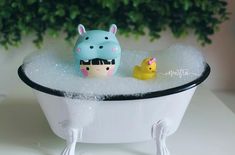 a bathtub with two rubber ducks in it and a toy rhinoceros sitting on the tub