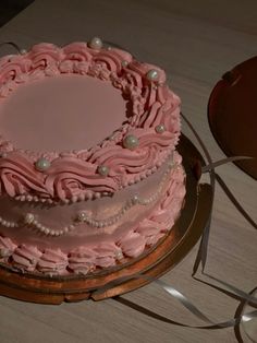 a pink cake sitting on top of a wooden table