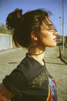 a woman is standing on the street with her hair blowing in the wind and looking off into the distance