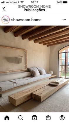 the room is decorated with wood beams and white linens, along with a large wooden bench