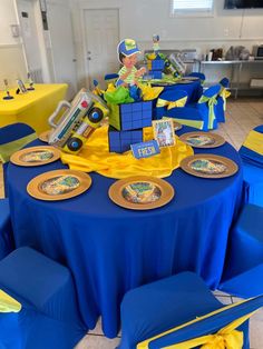 a table with blue and yellow tables cloths, plates and napkins on it