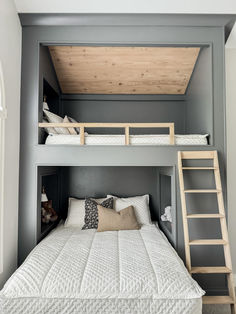 a bunk bed with two ladders is in the middle of a room that has gray walls