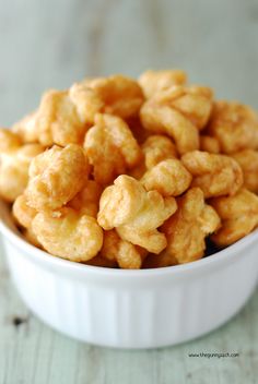 a white bowl filled with fried food on top of a wooden table