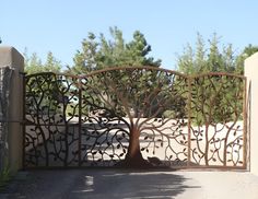 an iron gate with a tree on the top and bottom part in front of it