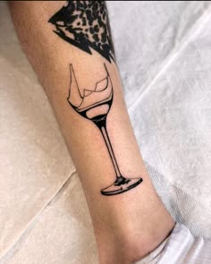 a person with a tattoo on their leg that has a wine glass and an umbrella in it